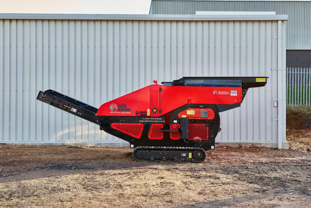 Side view of Red Rhino's 5000+ jaw crusher in red against a wall