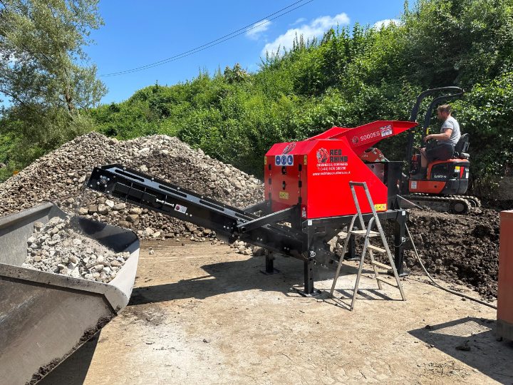 Powerful Red Rhino 5000ES static electric jaw crusher processing aggregate. Efficient material recycling with operator and excavator.